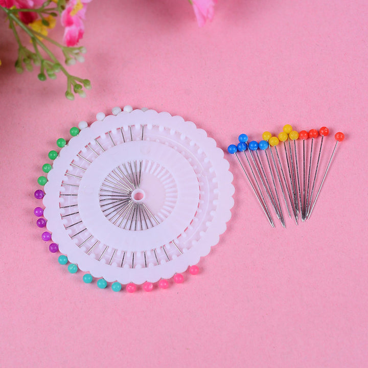 Colorful sewing pins arranged on white circular holders on a pink background for Monochrome Paper Craft Kit