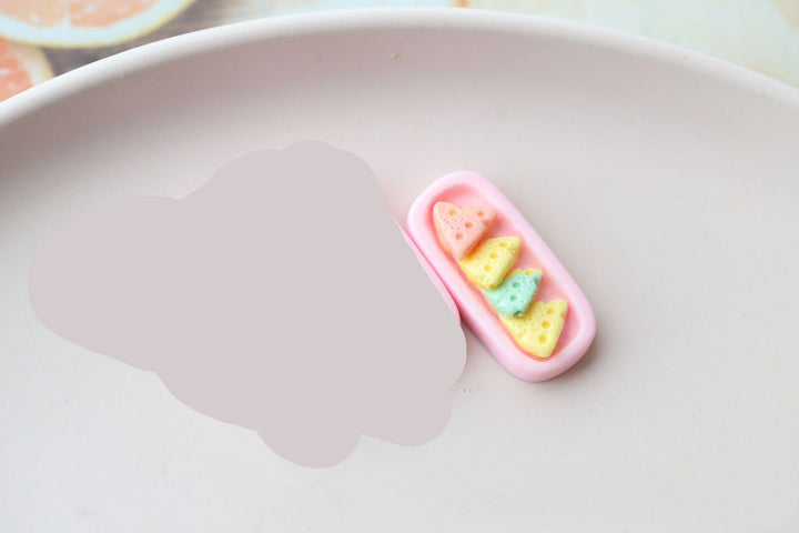 Colorful resin ornament accessories with miniature fruit designs from Arts And More on a pale pink plate