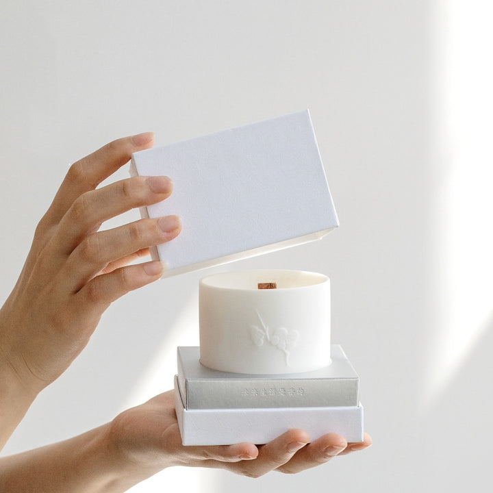 Person unboxing Snow Moon Scented Candles in elegant packaging for a calming ambiance
