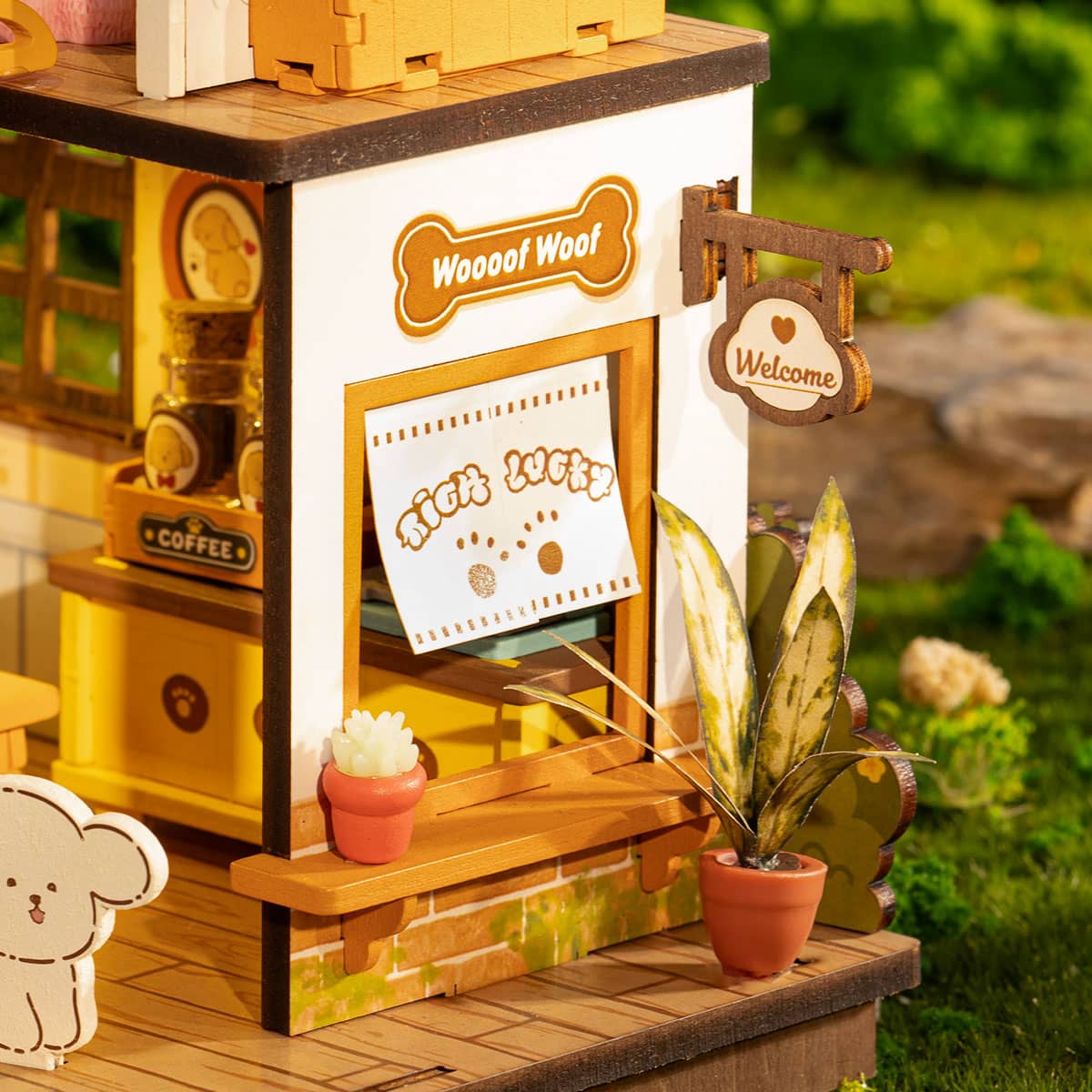 Miniature dog-themed coffee shop with 'Woof Woof' sign and plants in a garden setting.