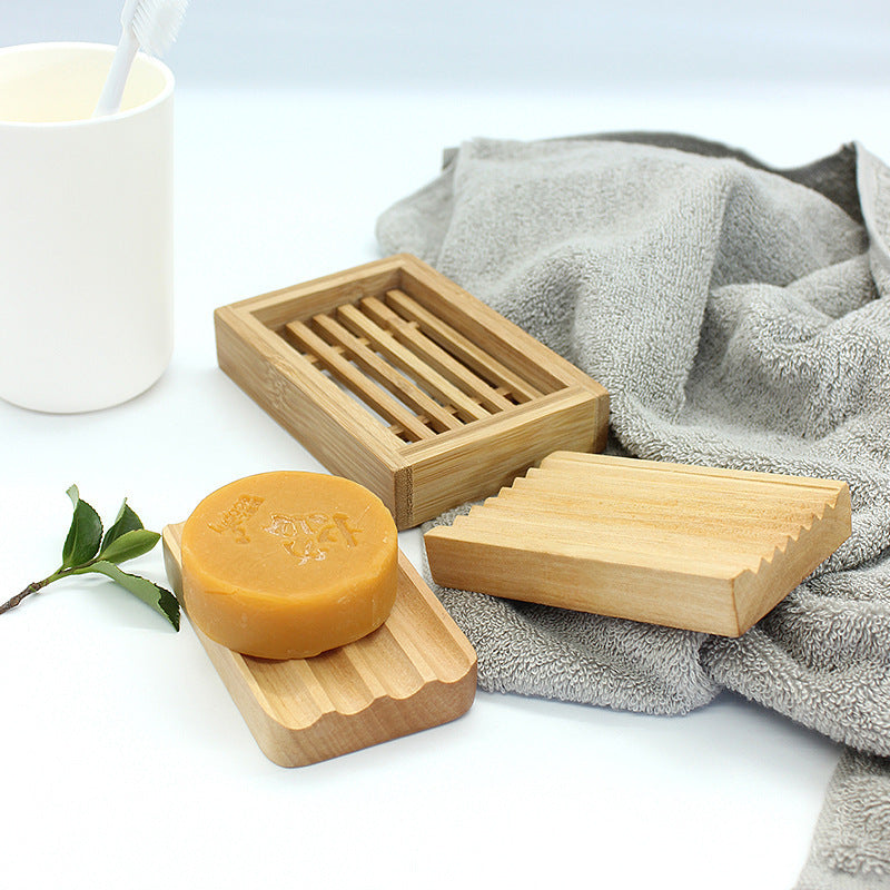 Bamboo Handmade Soap Holder with slotted design next to round handmade soap and gray towel