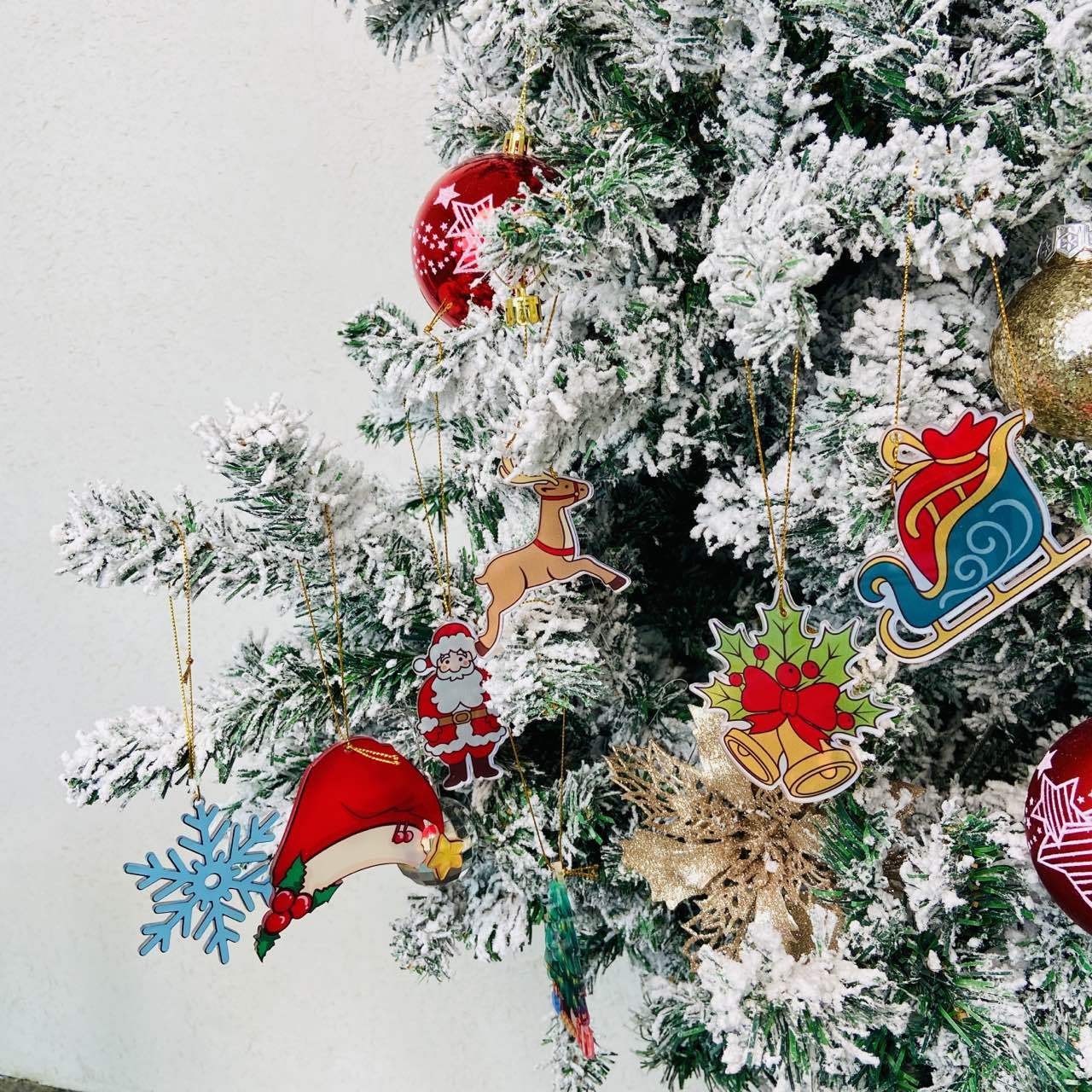 Colorful Christmas Decor Pendants hanging on a snow-covered Christmas tree for festive decoration