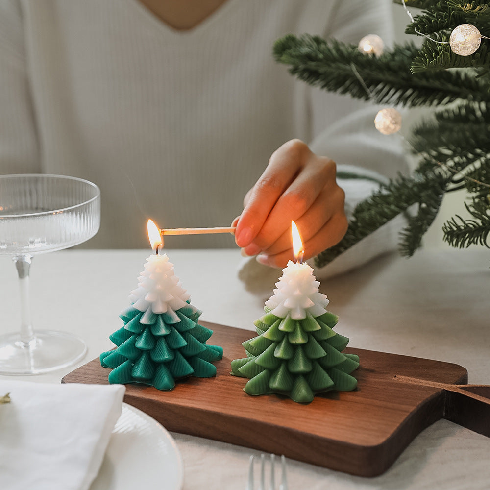 Person lighting a Christmas Tree Scented Candle on a wooden tray near a festive table setting