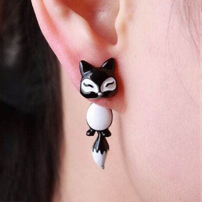 Black and white fox shaped Clay Animal Earrings worn on ear by person
