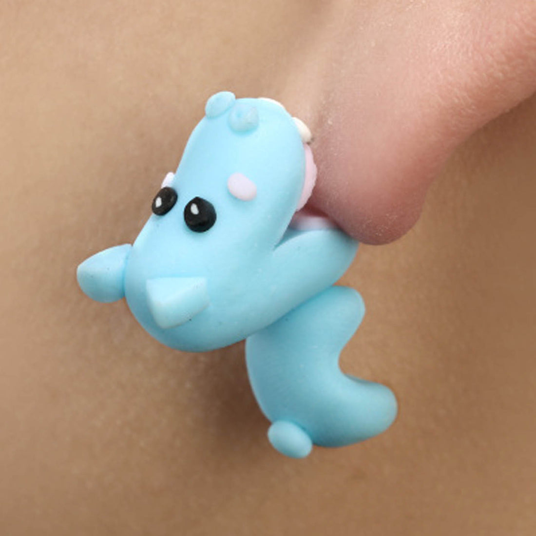Blue clay animal earrings shaped like a cute creature worn on ear with black eyes and small pink details