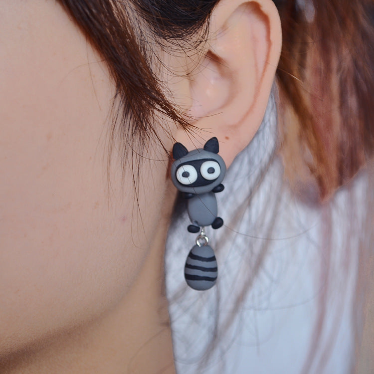 Black and gray Clay Animal Earrings shaped like a cute cat worn on a woman's ear from Arts And More