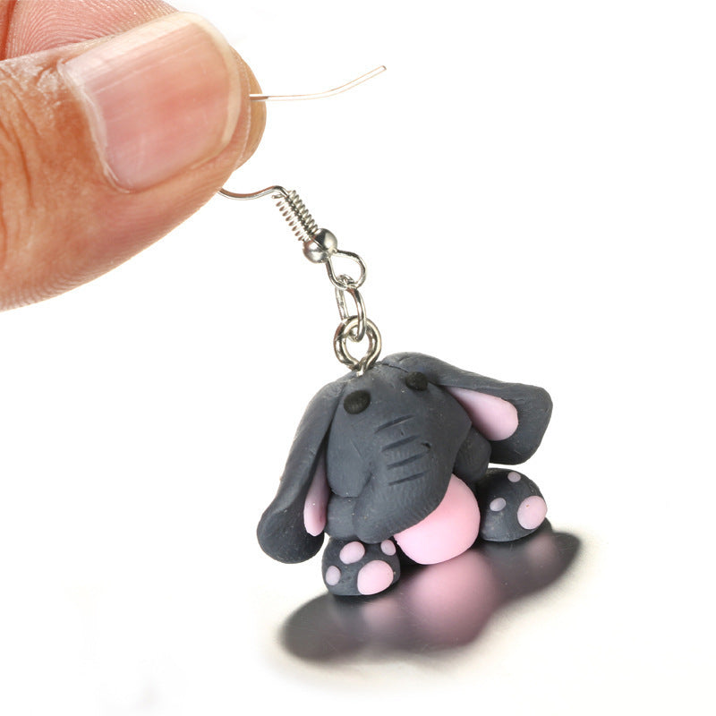 Hand holding Arts And More clay animal earrings shaped like a cute gray and pink elephant