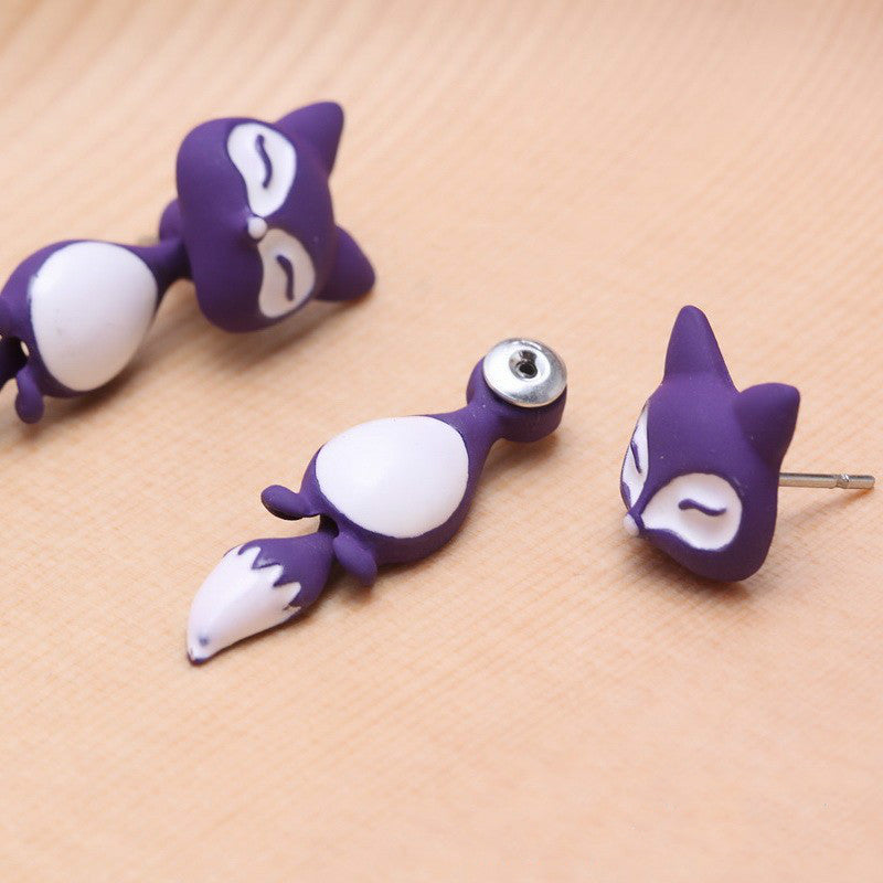 Arts And More purple and white Clay Animal Earrings shaped like foxes on a wooden surface