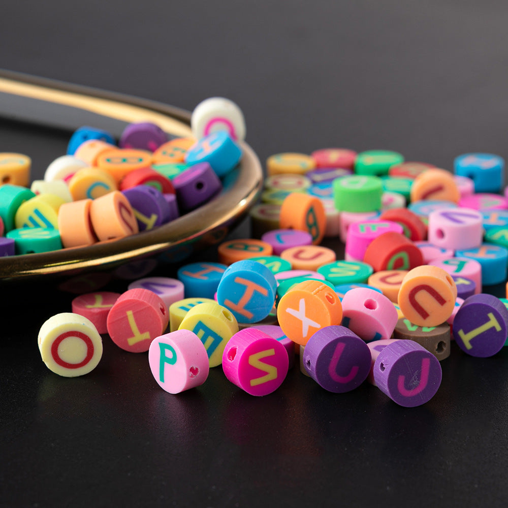 Colorful letter beads spilled from a gold tray for bracelet kit craft materials by Arts And More