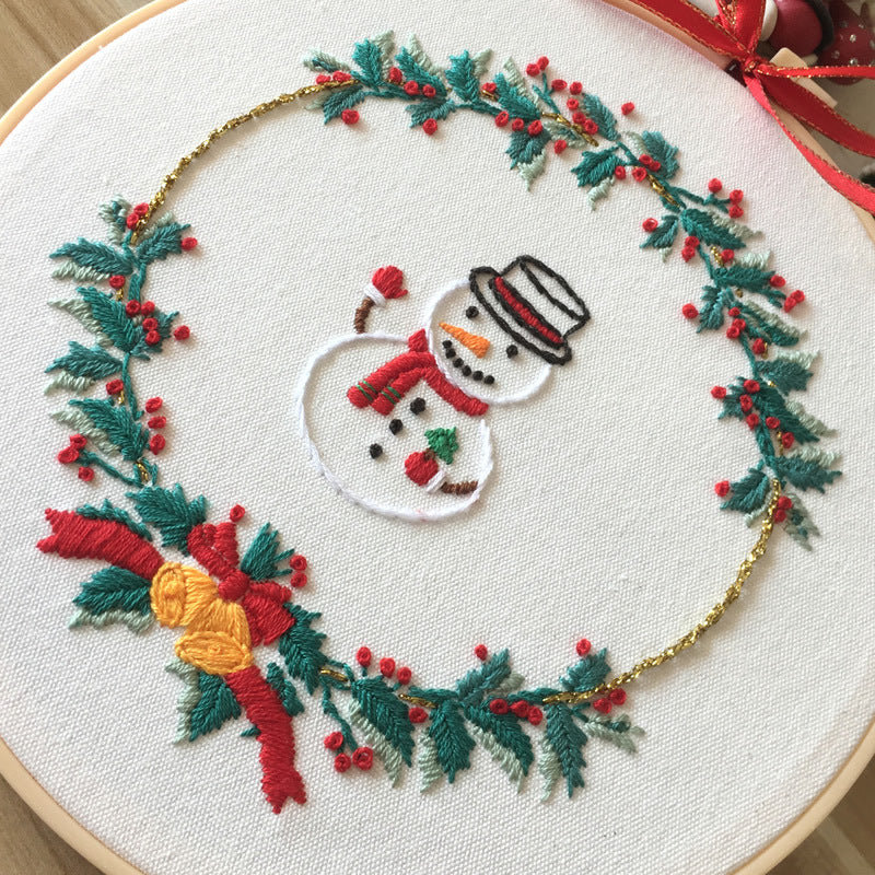 Festive cross stitch kit featuring a snowman surrounded by a colorful wreath design