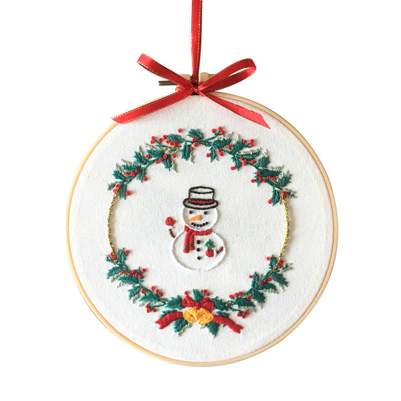 Festive Cross Stitch Kit featuring a snowman surrounded by a wreath with red ribbons