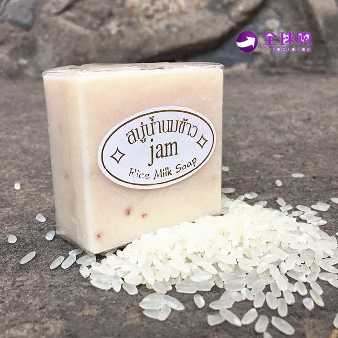 Arts And More Jasmine Rice Soap bar next to white rice grains on a stone surface