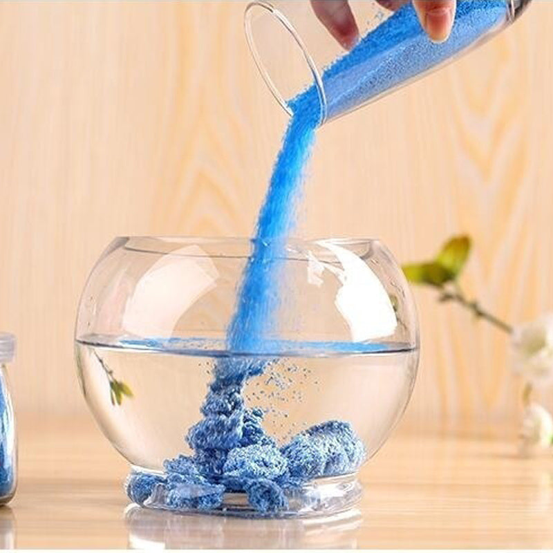 Blue Magic Sand from Arts And More Kids DIY Kits being poured into a glass bowl with water