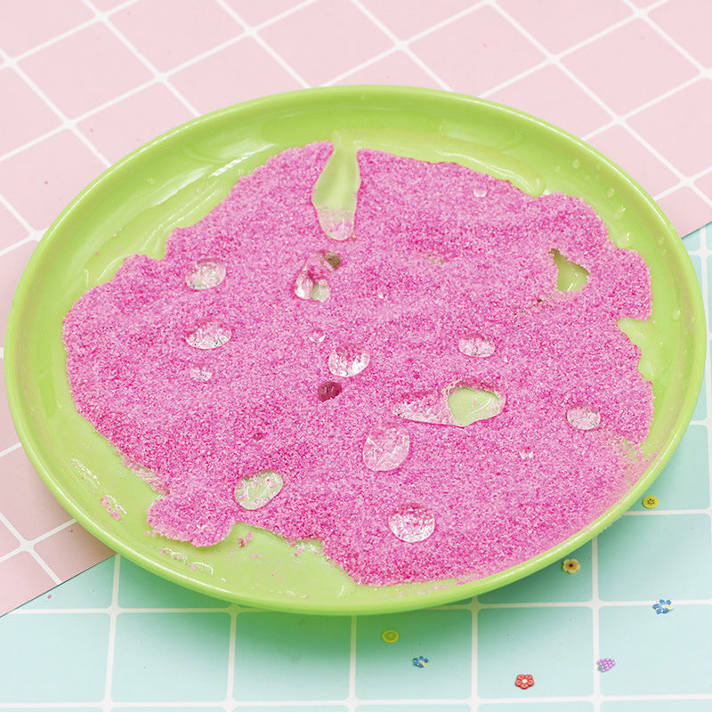 Arts And More Kids DIY Kits pink Magic Sand spread on a green plate with water droplets