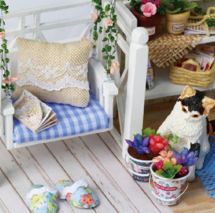 Miniature Doll House with a cozy bench, floral decor, and a cute cat figure surrounded by colorful plants
