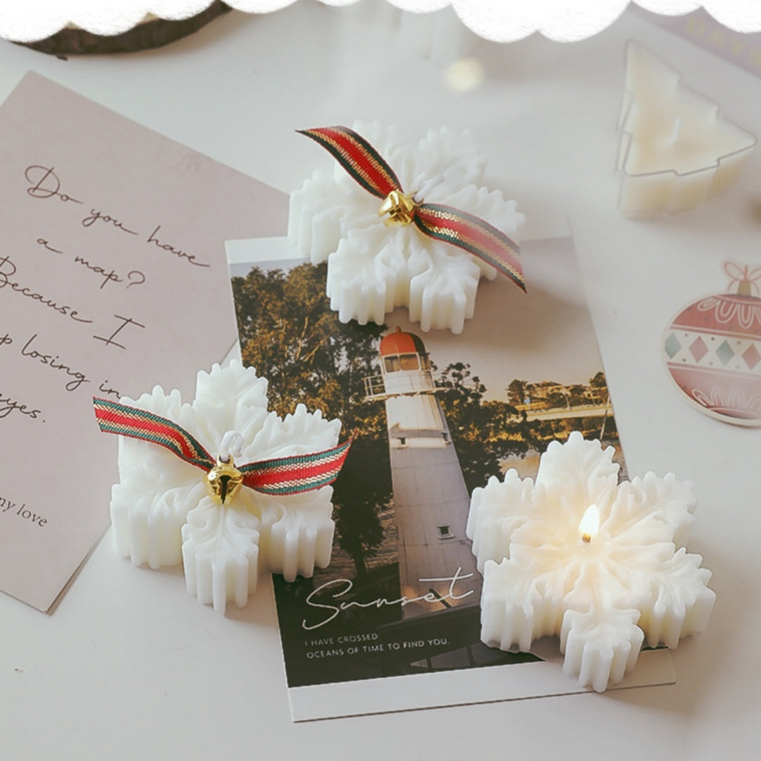 Snowflake Christmas Candle Gift in White with Decorative Ribbons on a Table with Cards