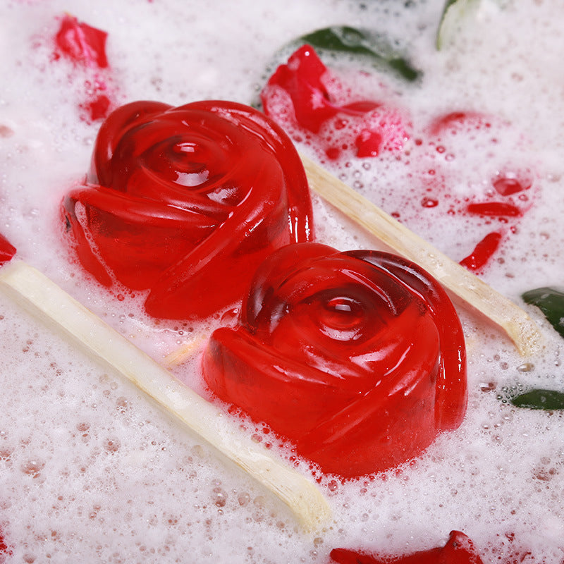 Red rose-shaped Rose Oil Soap by Arts And More submerged in foamy water with rose petals