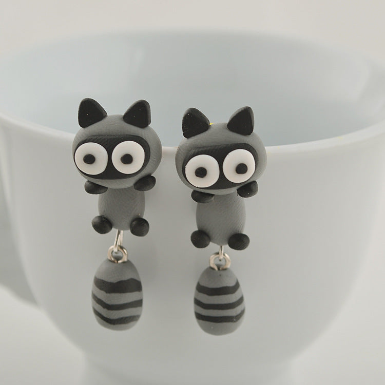 Arts And More Soft Clay Earrings shaped like cute gray raccoons with big eyes and striped tails