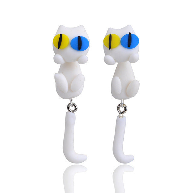 Arts And More Soft Clay Earrings shaped like white cats with blue and yellow eyes and dangling tails