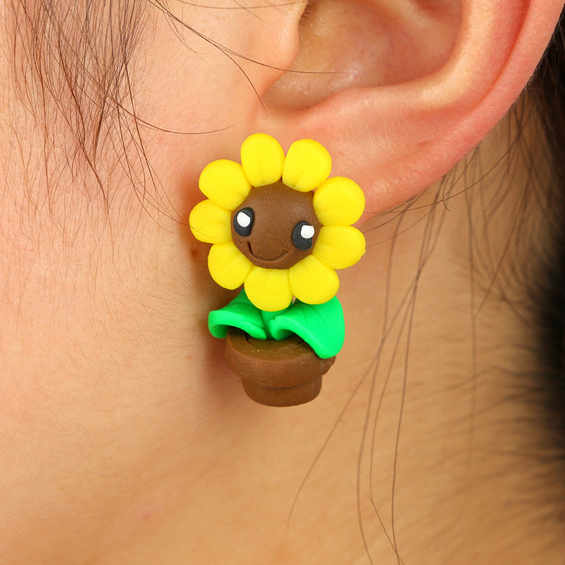Yellow sunflower soft clay earrings with smiling face and green leaves worn on ear