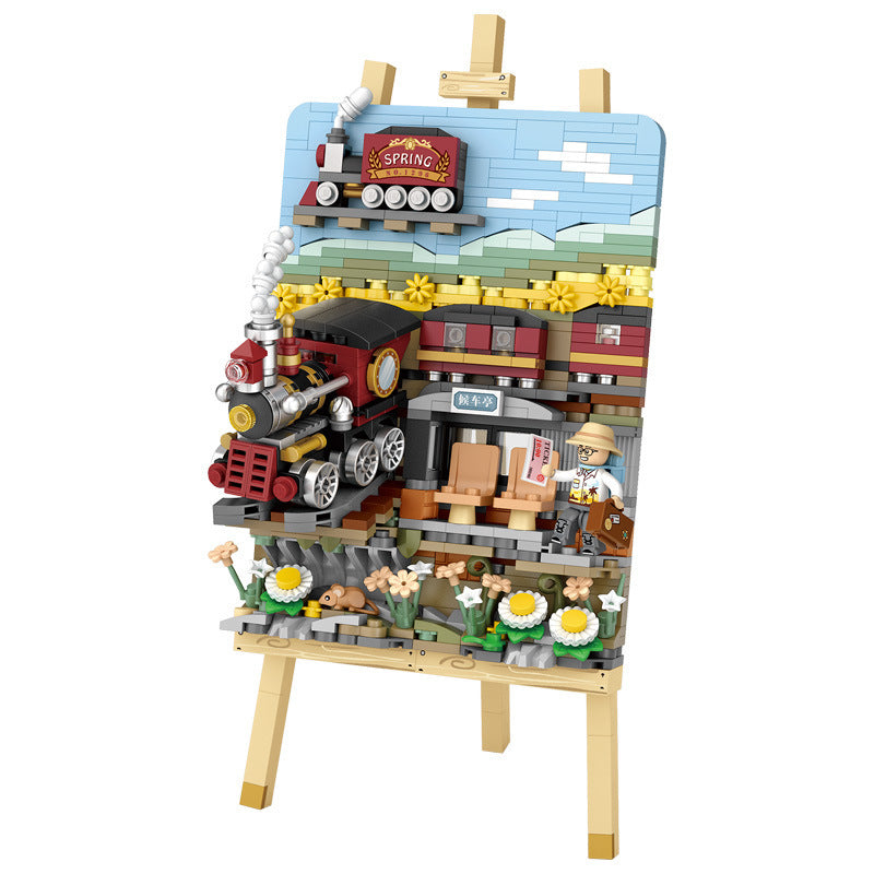 Stereograph Small Particle Building Blocks set featuring a colorful train and a spring scene on an easel
