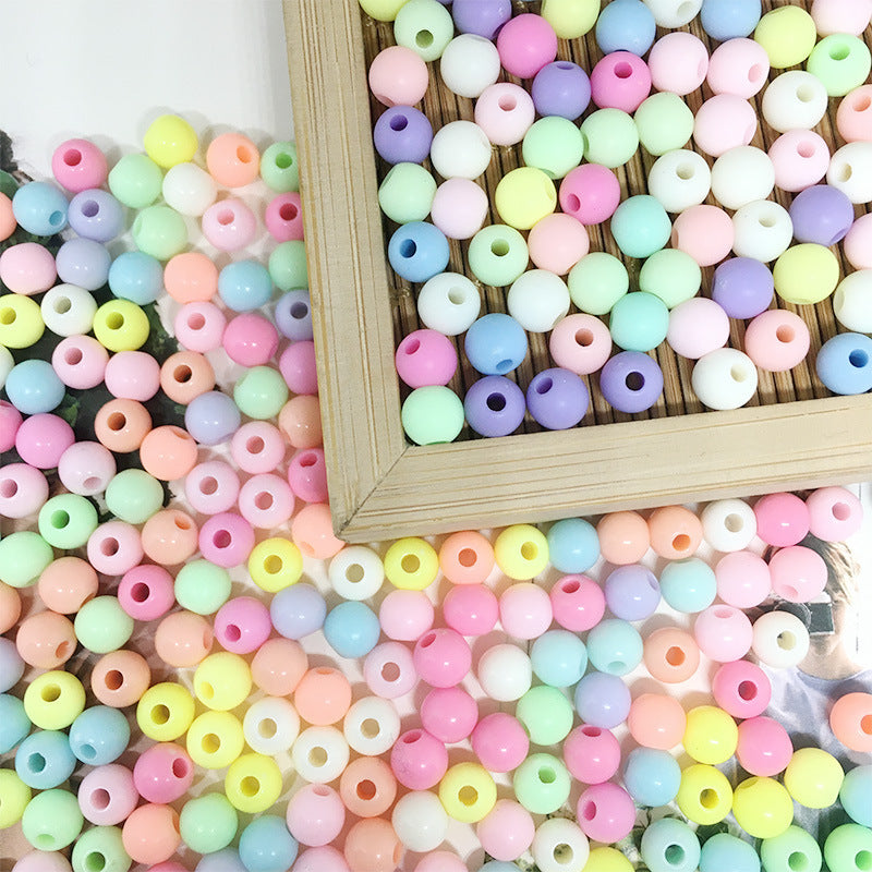 Arts And More Acrylic Round Beads in pastel colors displayed with a wooden frame for craft projects