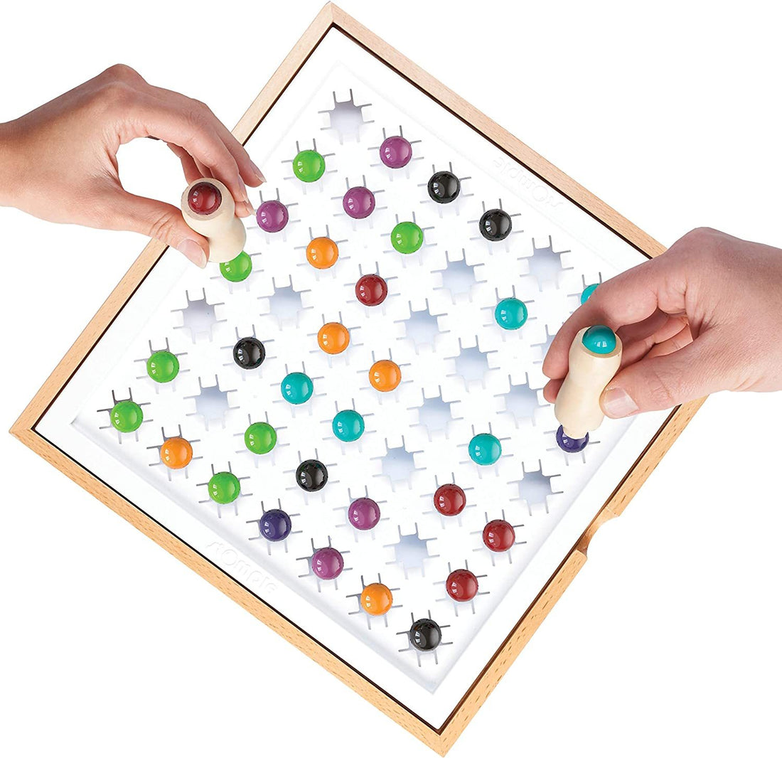 Hands playing Arts And More Marble Stomping Game with colorful marbles on wooden board